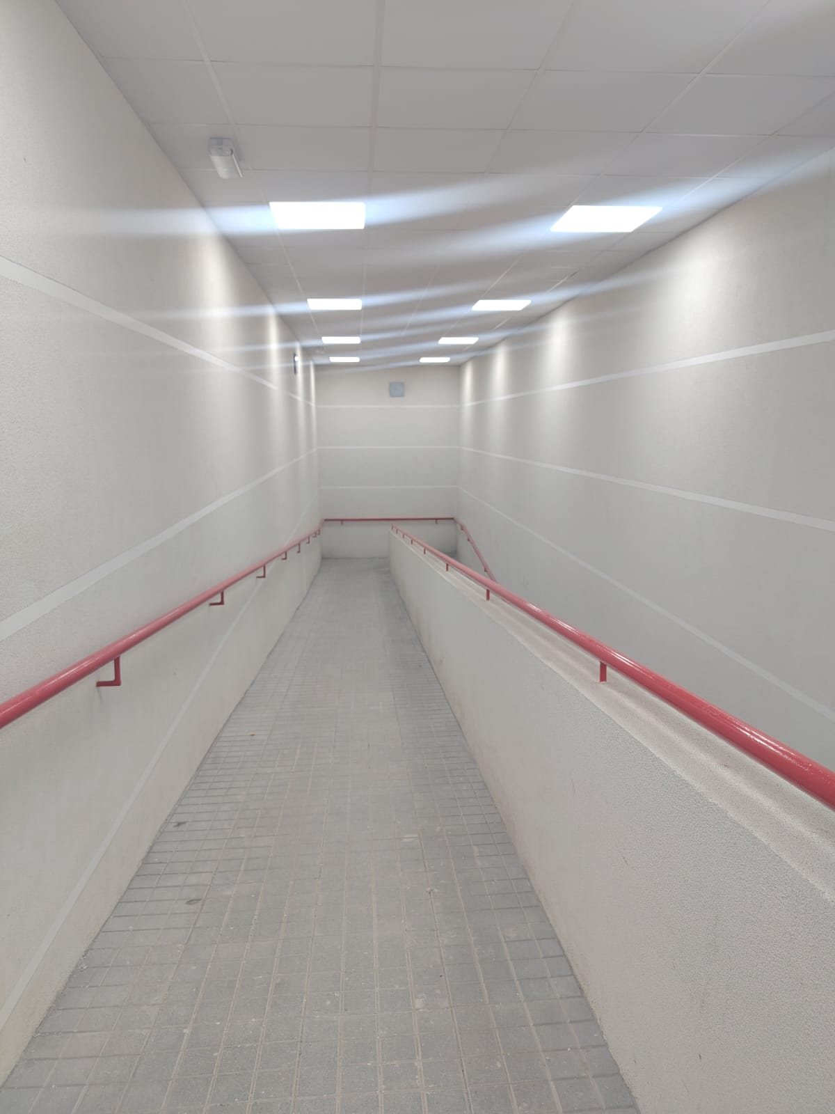 Rampa peatonal con iluminación empotrada en cielo modular